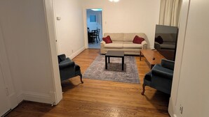 Un salon doté d’un parquet, d’un canapé, d’une table basse et d’un téléviseur.
