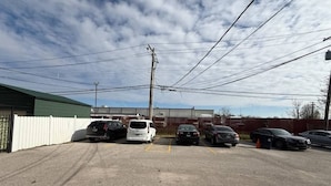 Un parking avec plusieurs voitures, un bâtiment doté d’un toit végétalisé et des lignes électriques aériennes.