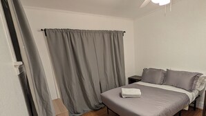 Une chambre à coucher avec un lit, un ventilateur de plafond et un plancher en bois.