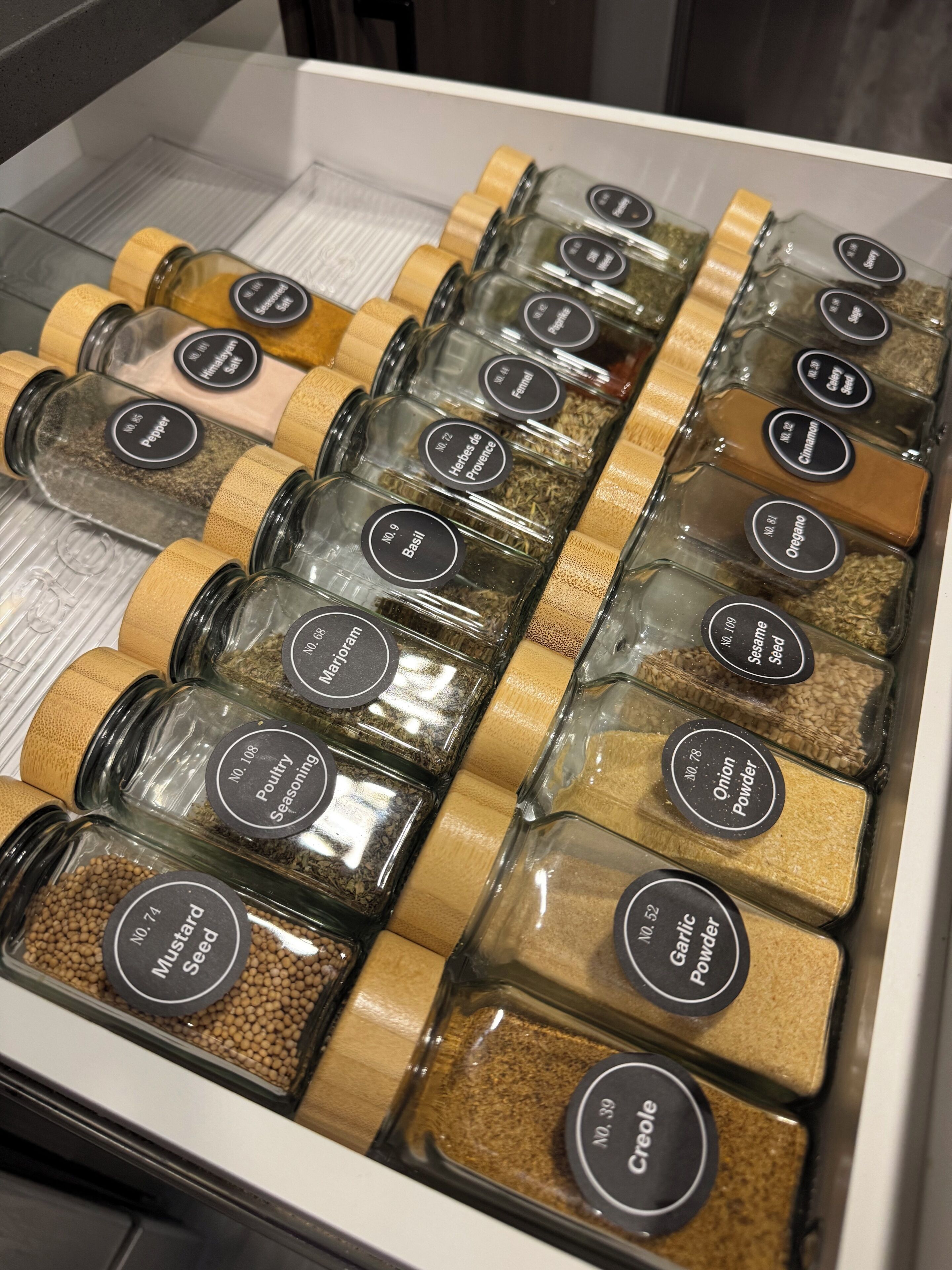 A box containing various glass jars with labels, each containing different spices and seasonings.