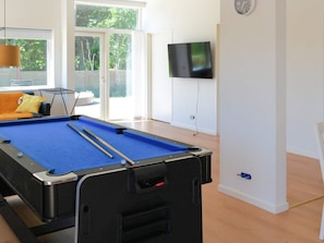 A pool table with cues, a sofa, a TV, and a clock on the wall. - 5 Star Holiday Home in Saltum (Saltum)
