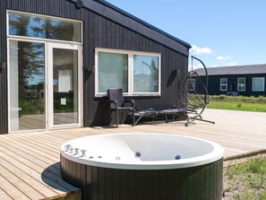 A modern building with a wooden deck, a hot tub, and outdoor seating. - 5 Star Holiday Home in Saltum (Saltum)