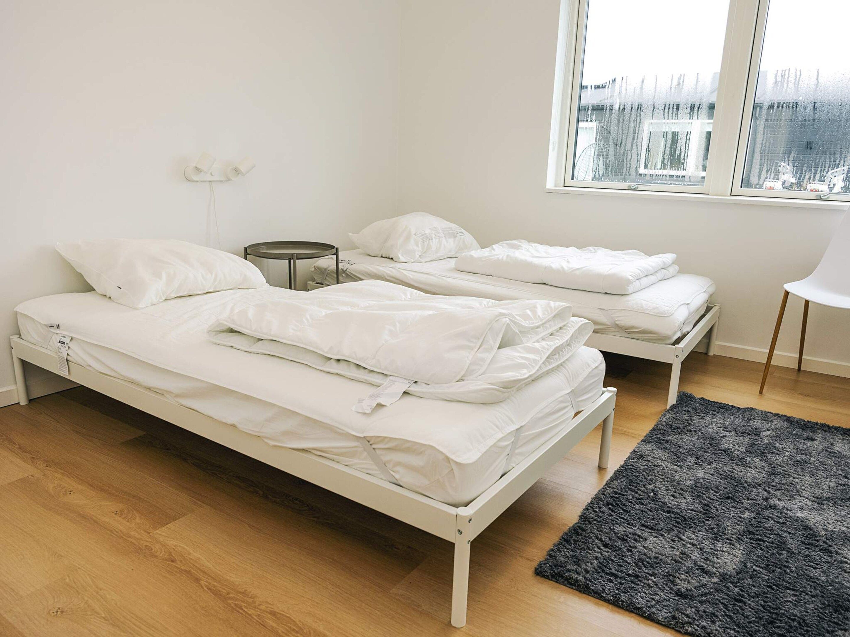 A room with two single beds, a small round table, and a window with a view of buildings.