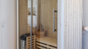 A sauna with a glass door, wooden benches, and a metal door handle. - 5 Star Holiday Home in Saltum (Saltum)