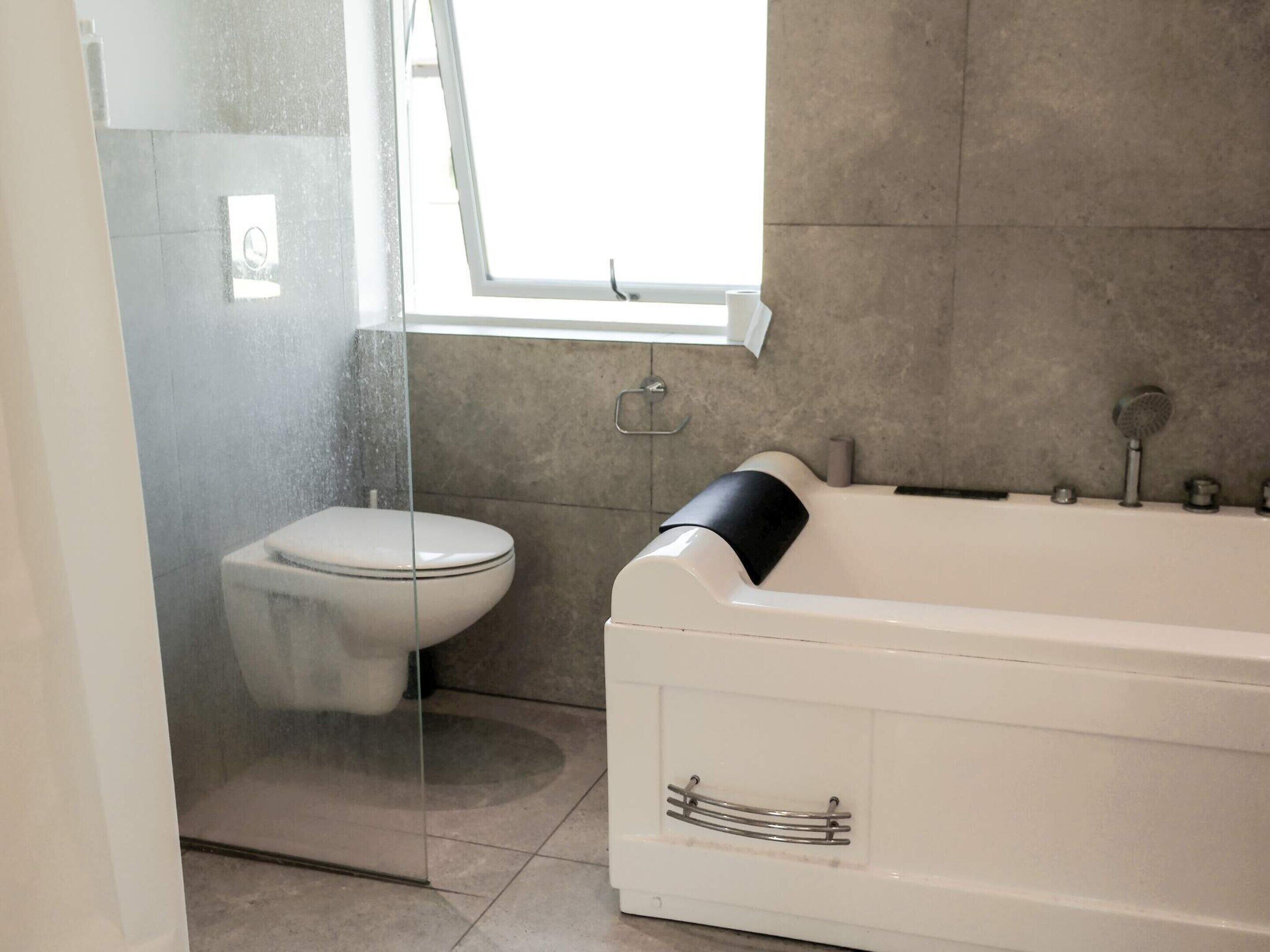 A bathroom with a glass shower enclosure, a toilet, and a bathtub.