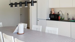 A modern kitchen with white cabinetry, a microwave, and a dining table with chairs. - 5 Star Holiday Home in Saltum (Saltum)