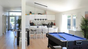 A modern kitchen with white cabinets, a dining area with white chairs, and a pool table. - 5 Star Holiday Home in Saltum (Saltum)