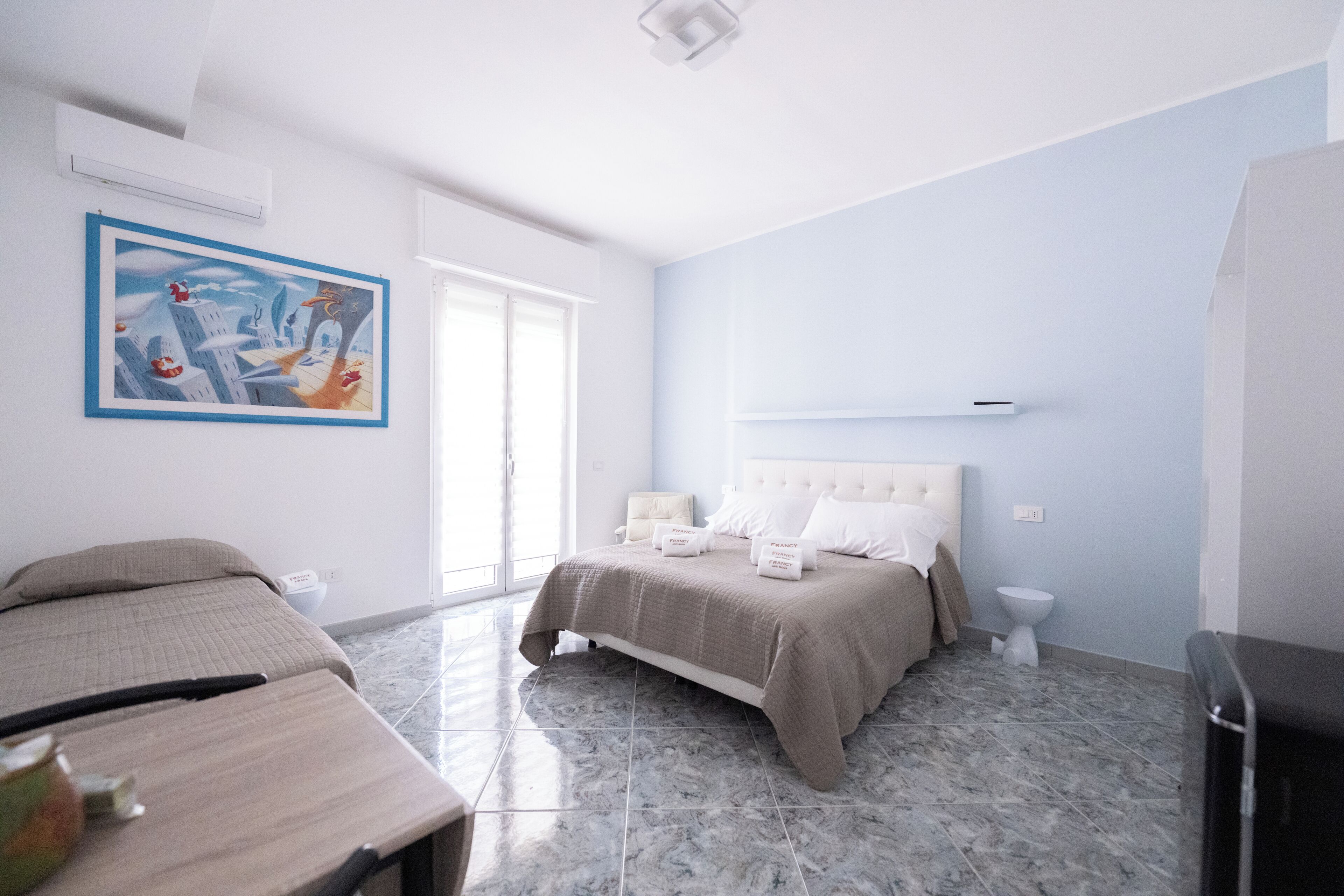A bedroom with a bed, bedside tables, a painting, and a window.