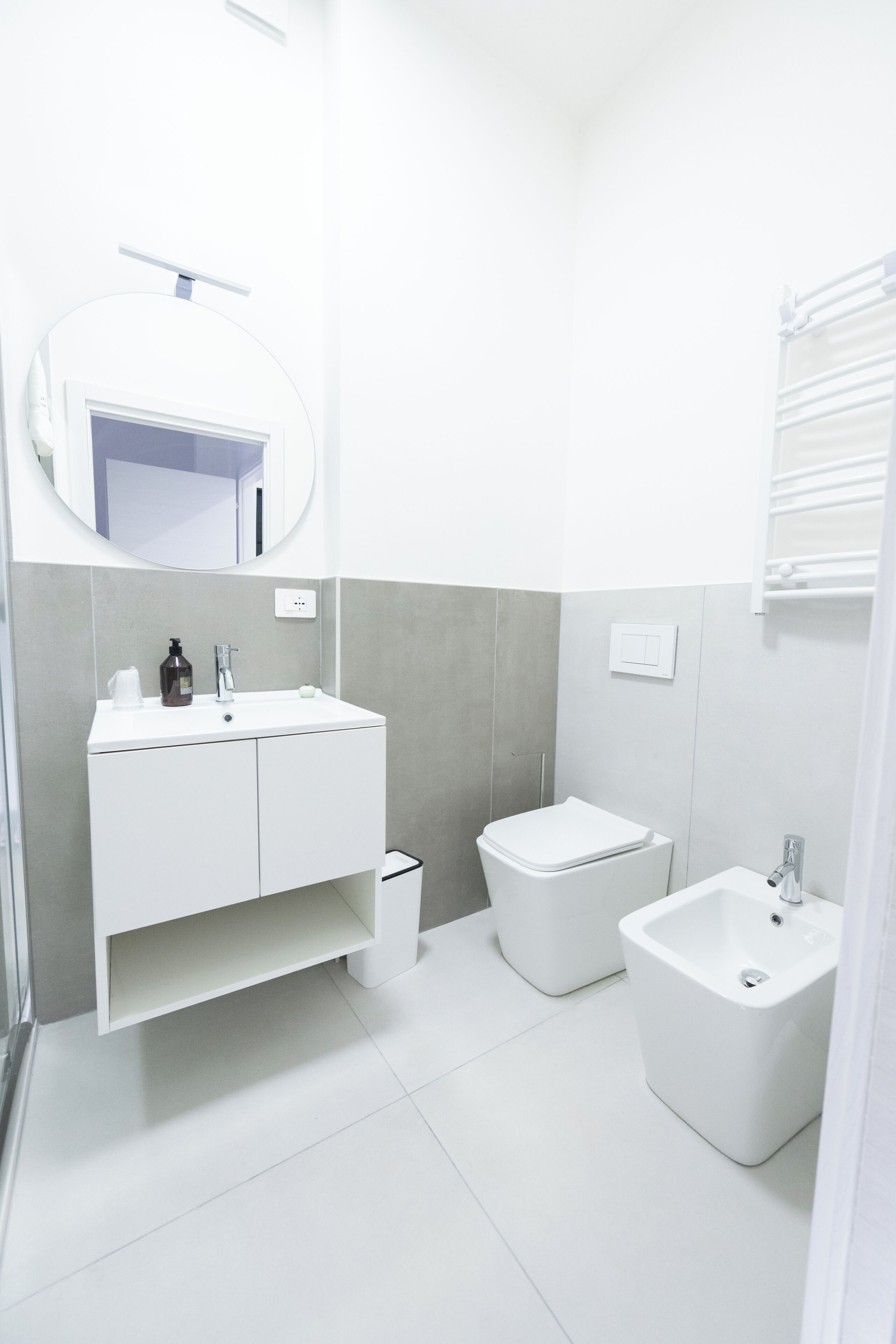 A modern bathroom with a white vanity, a toilet, and a bidet.