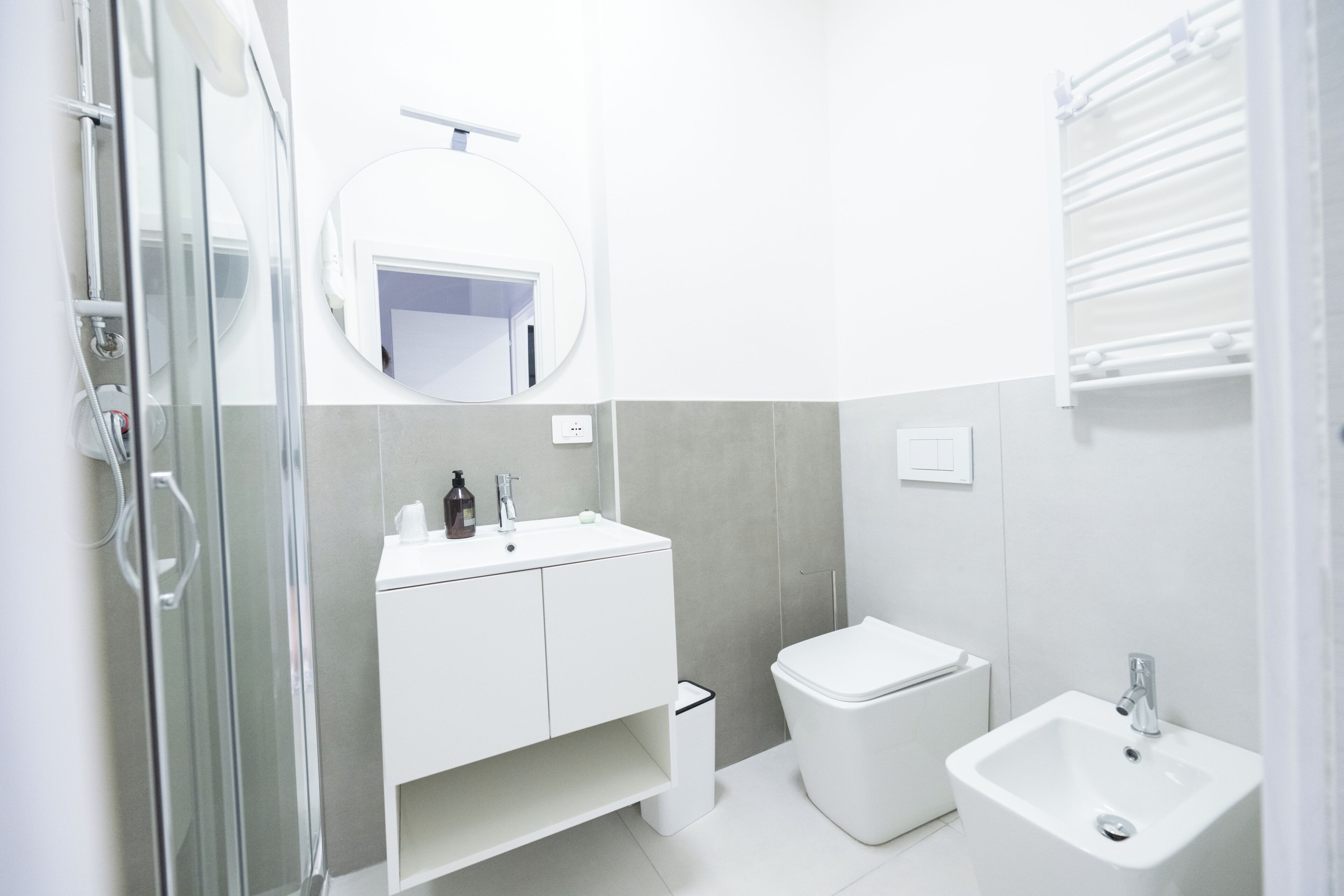 A modern bathroom with a glass shower enclosure, a white sink, a toilet, and a bidet.