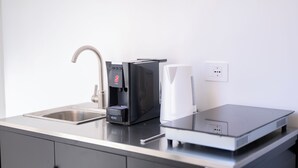 Ett modernt kök med en kaffebryggare, en vattenkokare och en bärbar dator på köksbänken.