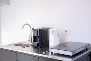 Una cocina moderna con cafetera, hervidor y una computadora portátil sobre la encimera.