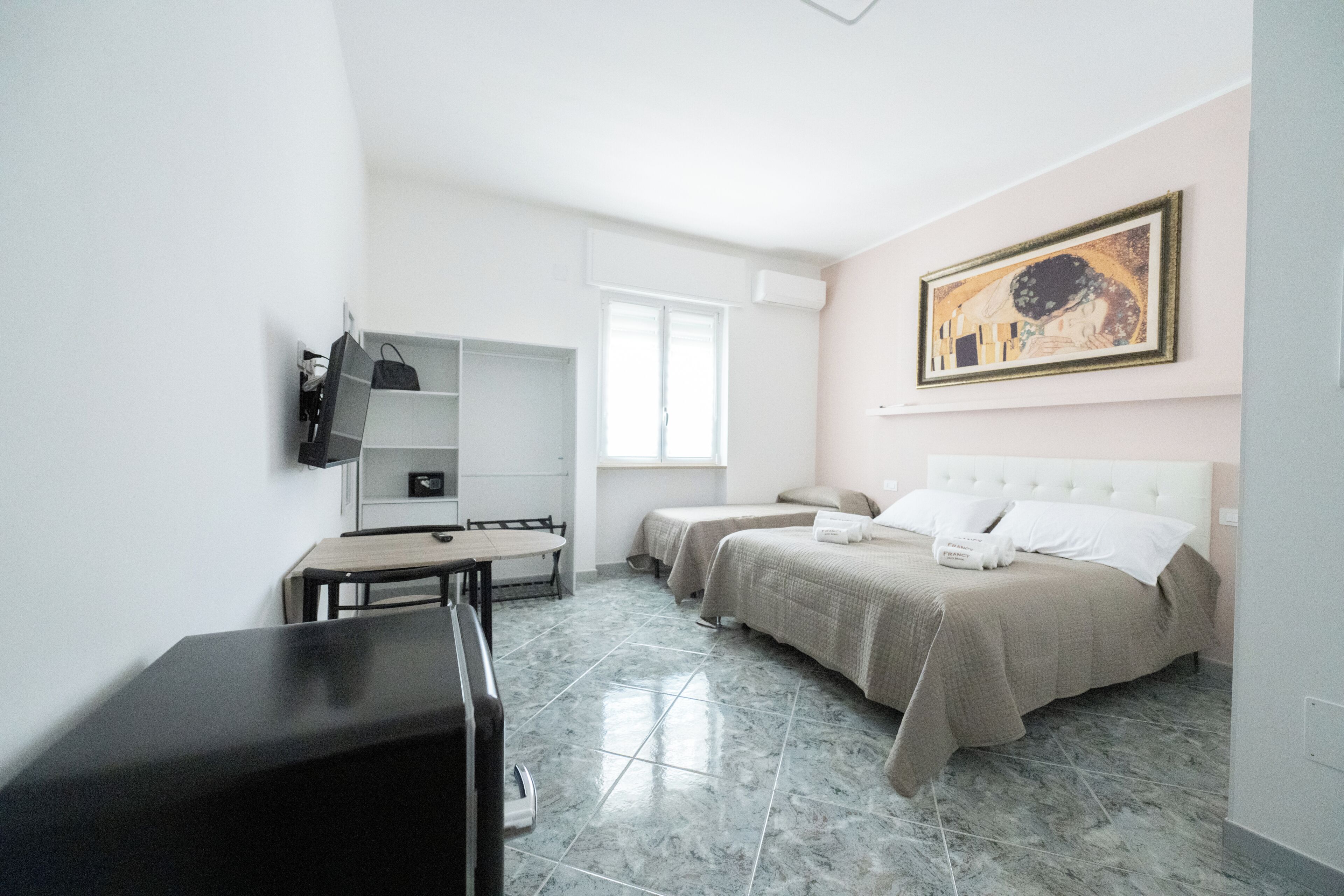 Ein Hotelzimmer mit Bett, Schreibtisch, Stuhl, Kleiderschrank und einem Bild an der Wand.