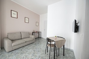 A living room with a sofa, a dining table, chairs, and framed pictures on the wall. - FRANCY AND SONS (Modugno)