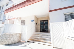 A building entrance with a set of stairs leading to a door, a metal fence, and a sign indicating the name of the building. - FRANCY AND SONS (Modugno)