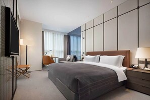 A modern hotel room with a large bed, a desk, a chair, and a TV. - WANDA YI CHENGDU (Chengdu)