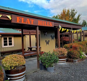 A building with a sign reading 'FLAT HILLS' and a covered patio area with potted plants. - Pod 3 at Flat Hills - Queen Pod (sleeps 2) (Mangaweka)