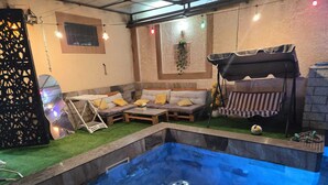 Ein Poolbereich mit Whirlpool, einer Sitzecke und einem kleinen Tisch.