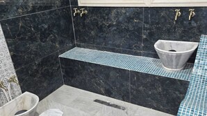 Ein Badezimmer mit Marmorboden, Waschbecken, Badewanne und Duschbereich.