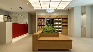 Zona de recepción con un escritorio de madera, un mostrador rojo de recepción y un quiosco de autoservicio.