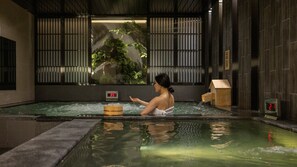 A woman in a traditional Japanese onsen with a wooden bucket, a wooden house-shaped structure, and a digital thermometer. - Anook Hotel & Spa Bucheon Sangdong (Bucheon)