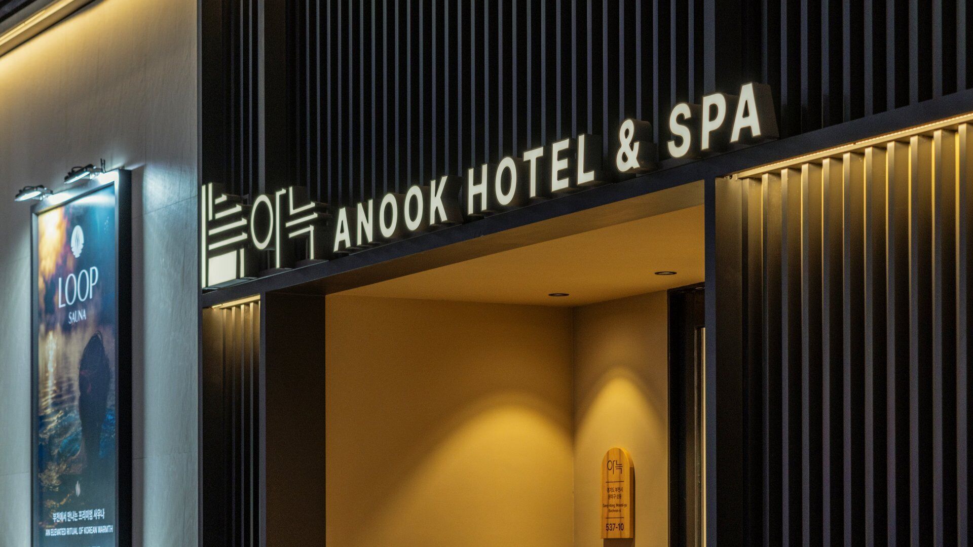 Exterior do Hotel & Spa Anook, com design moderno, destacando uma placa e um cartaz do serviço LOOP sauna.