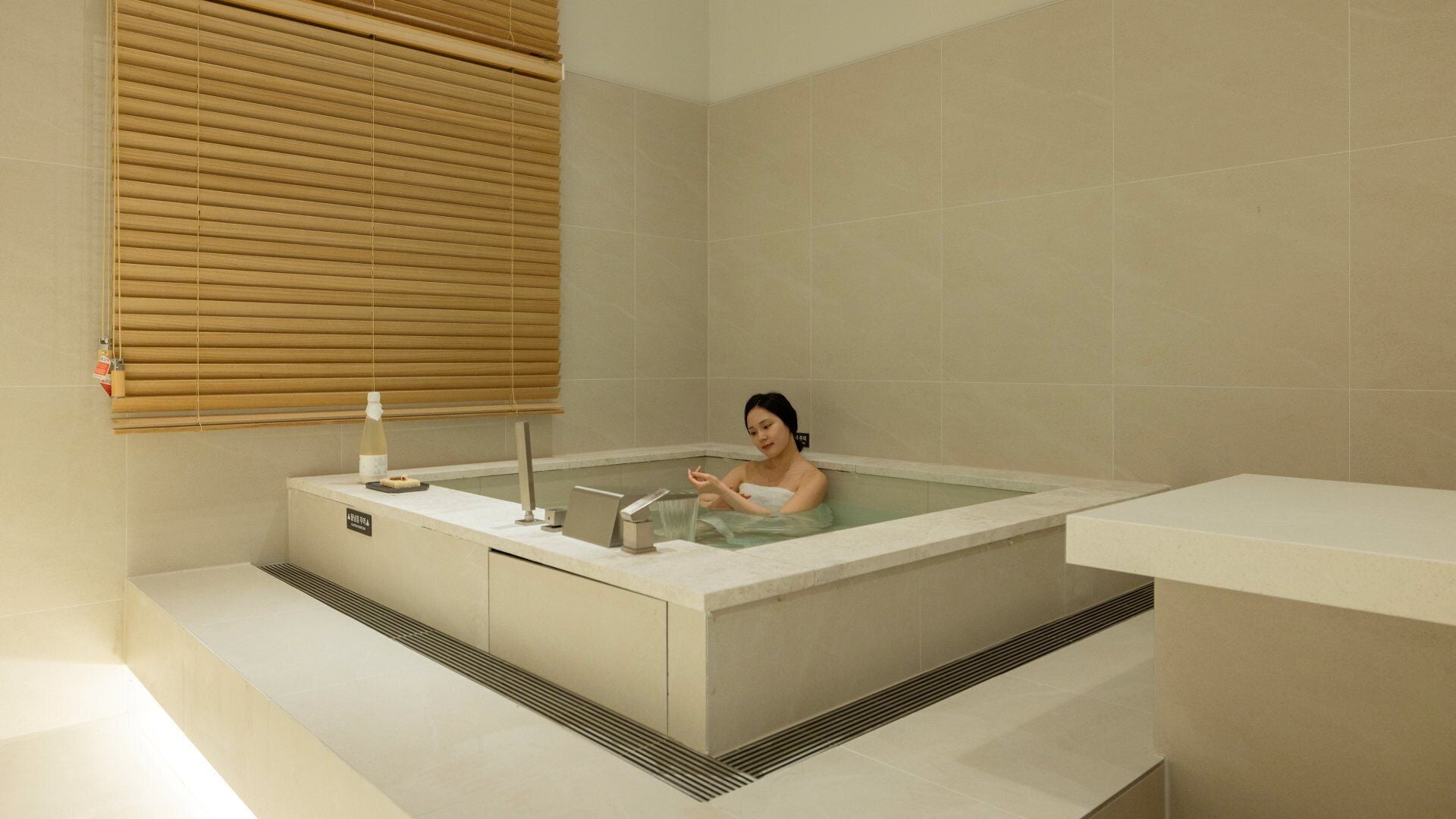 A modern bathroom with a bathtub, a towel rack, and a bottle of lotion.