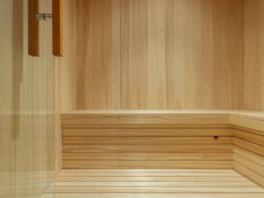 Una sauna de madera con un banco y un calentador fijado a la pared.