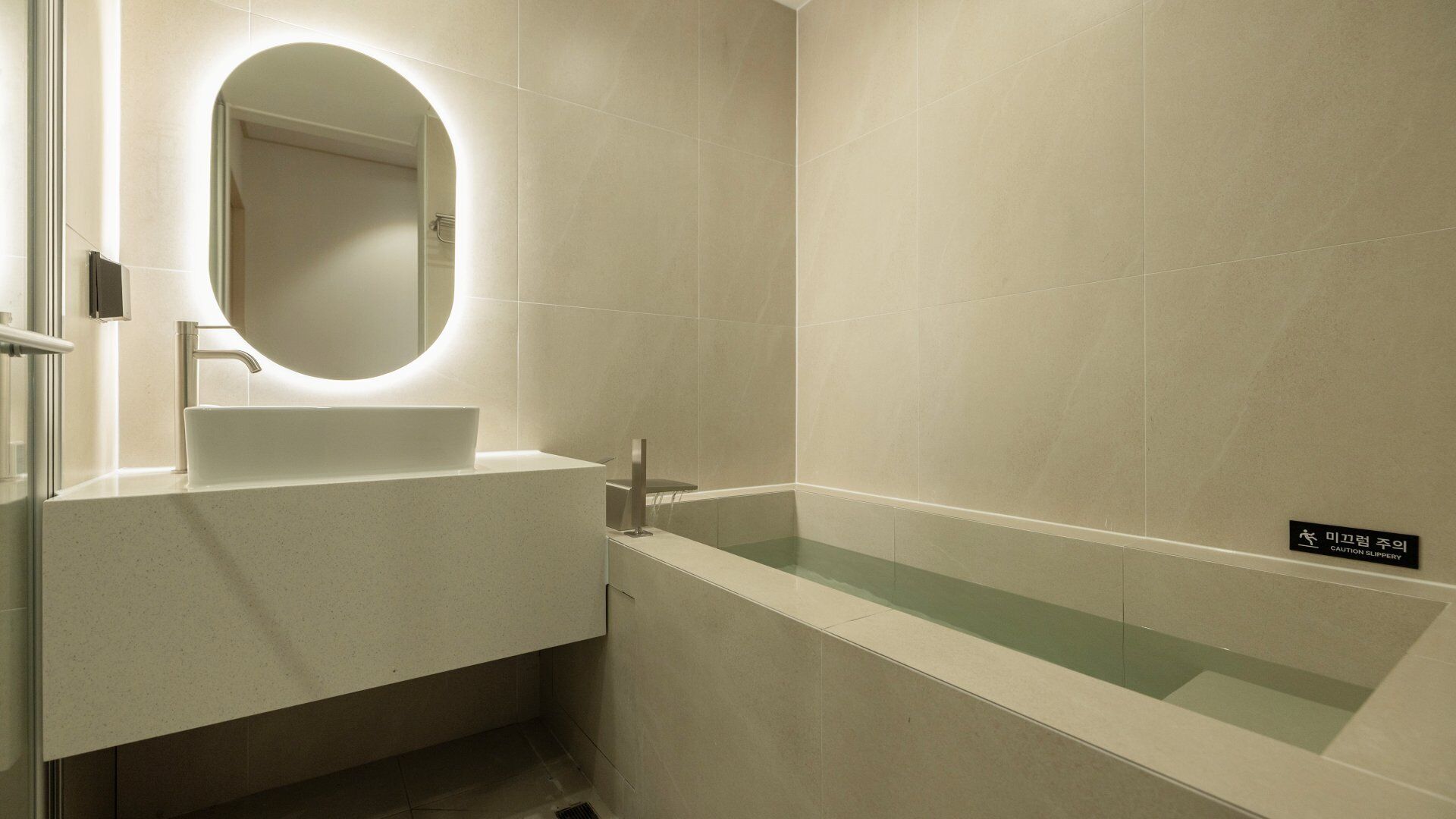 Un baño moderno con lavamanos, espejo y bañera.