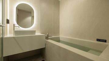 Un baño moderno con lavamanos, espejo y bañera.