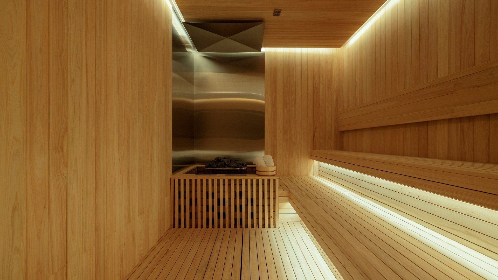 A sauna with wooden walls and benches, a bench with towels, and a bench with a tray.