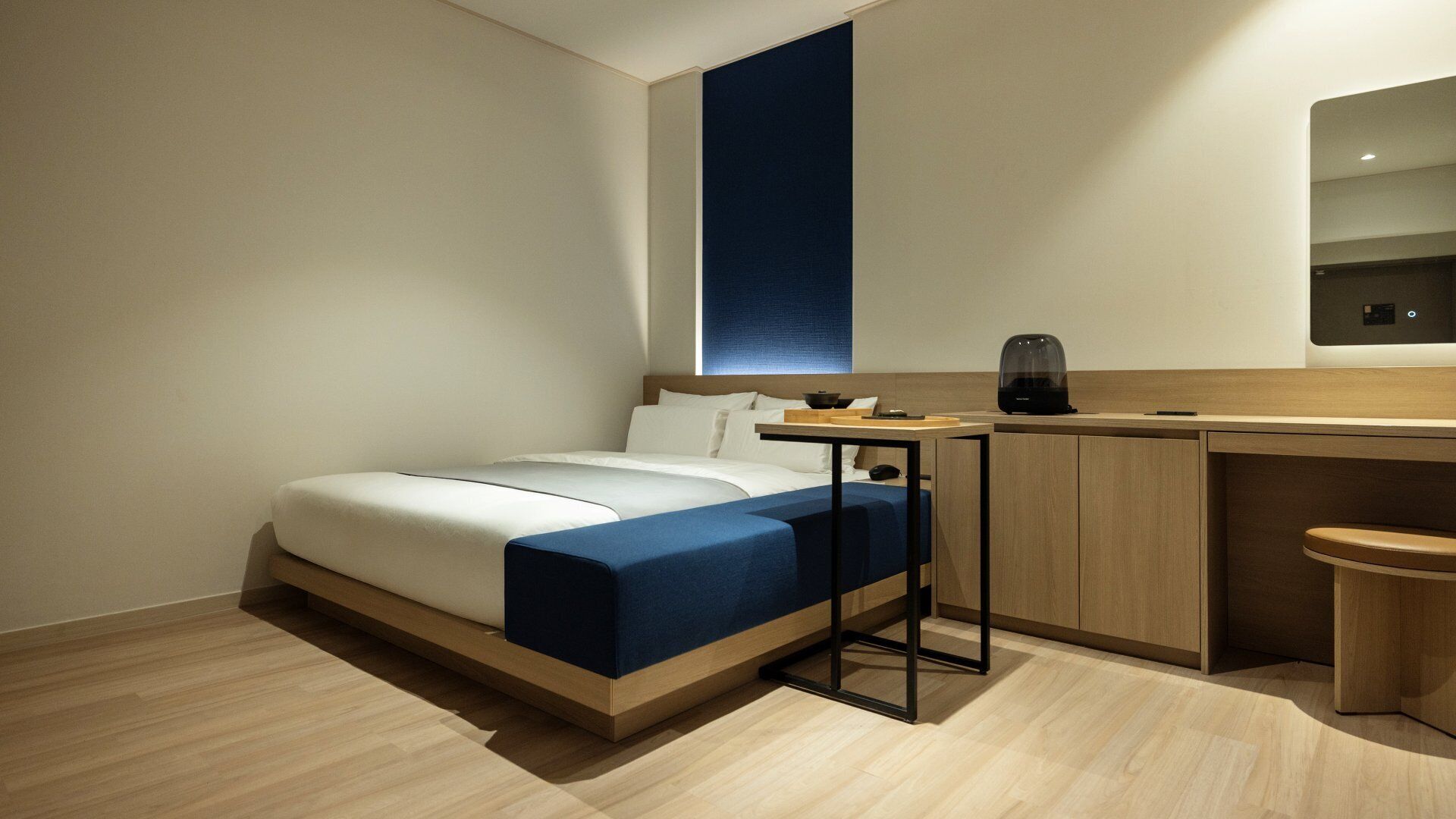 Een moderne hotelkamer met een bed, een bureau en een zithoekje.