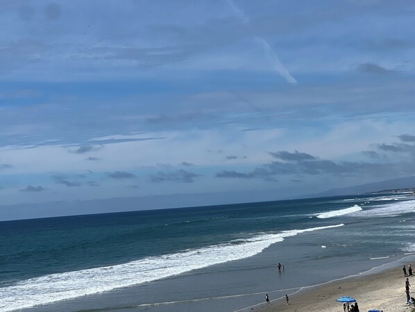Ein Strand mit Wellen, Menschen und blauem Himmel.