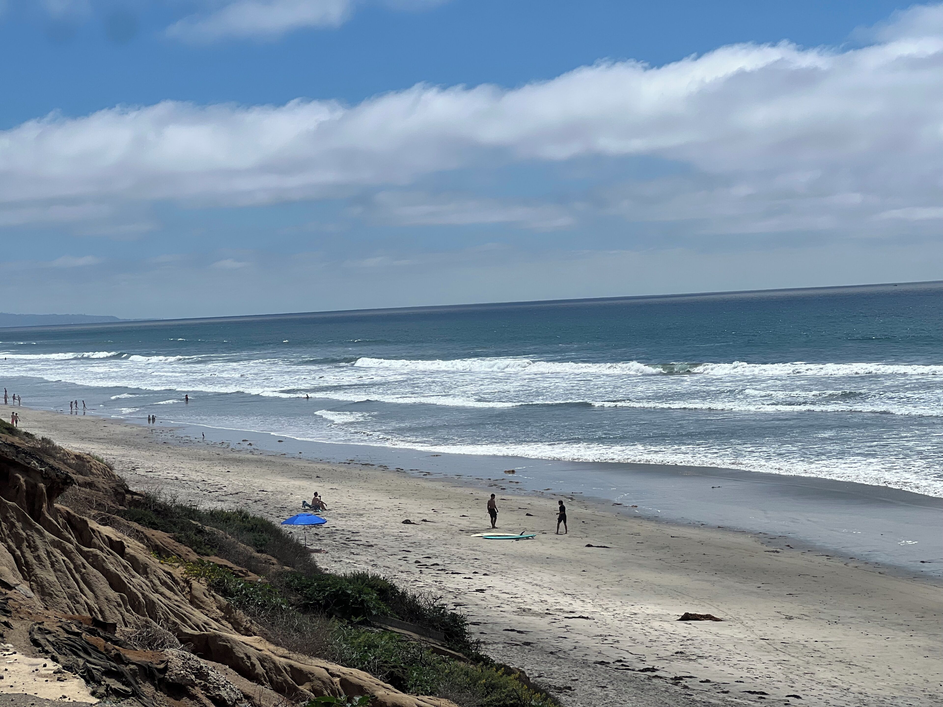 Une plage avec des vagues, des gens et un ciel dégagé.