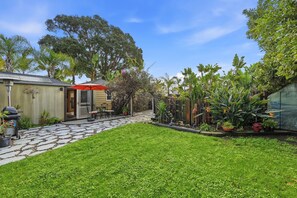 Ein Garten mit Terrasse, Grill und verschiedenen Pflanzen.