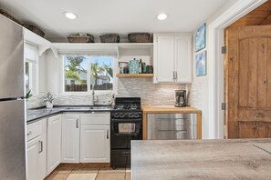 A kitchen with white cabinets, a black stove, and a wooden countertop.