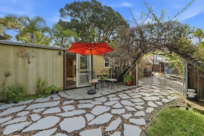 A patio with stone flooring, a red umbrella, and a seating area with a table and chairs. - Walk to the Beach... (Carlsbad)