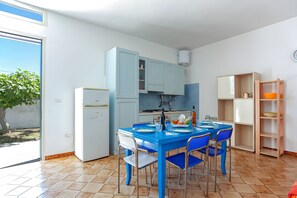 Una cocina con una mesa azul, armarios blancos y vistas al exterior.