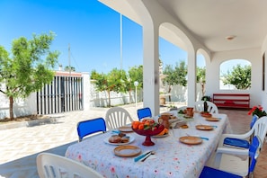 An outdoor dining area with a table set for two, surrounded by blue chairs, under a white structure with arches. - Casa Spiaggiabella Near The Sea (Lecce)