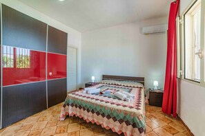 A bedroom with a bed, a nightstand, a wardrobe, and a window with curtains.