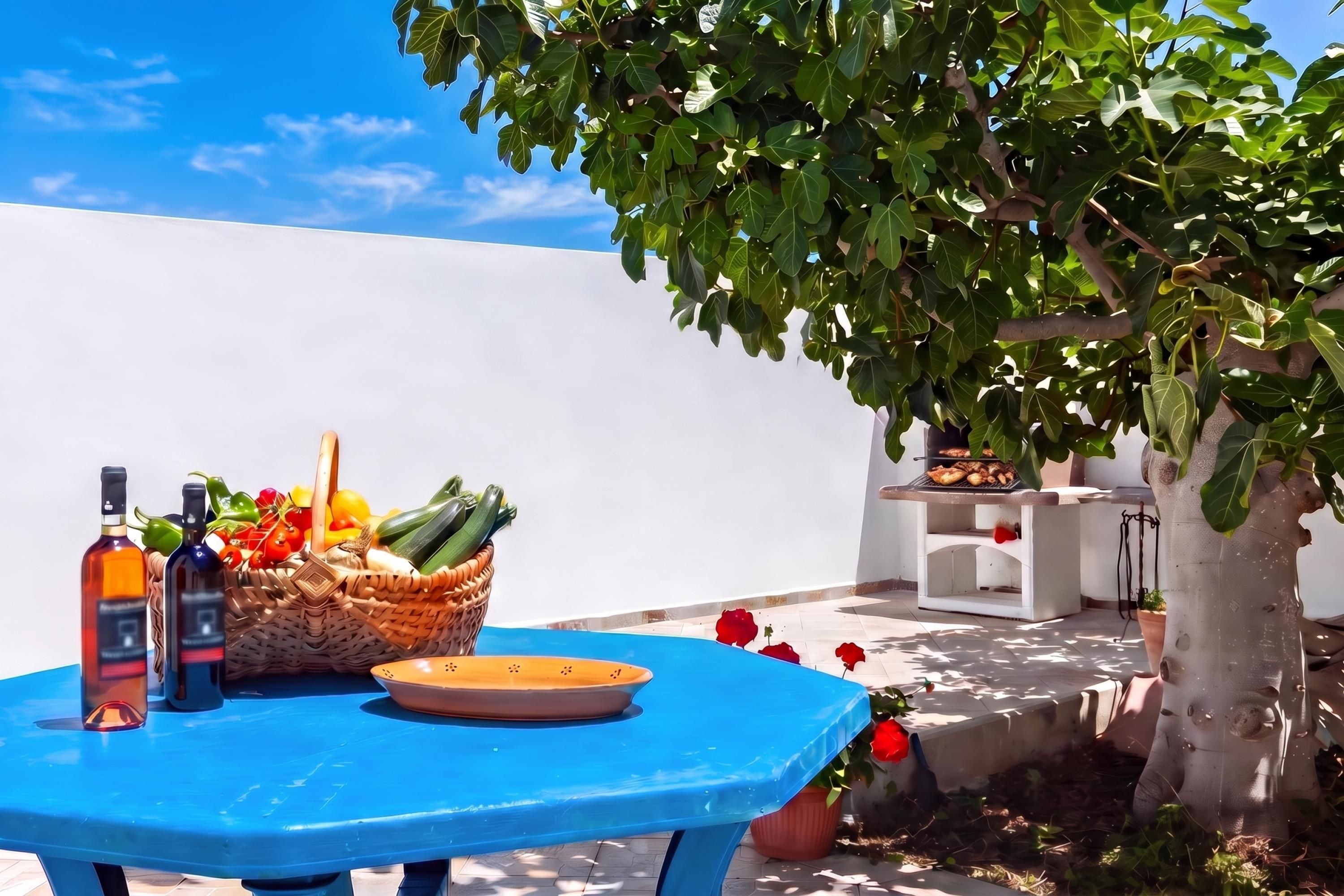 Uma mesa azul com garrafas, uma cesta de legumes e um prato.