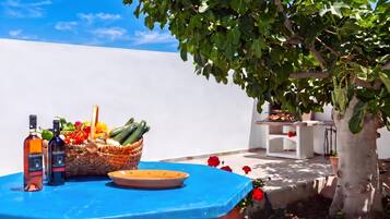 Uma mesa azul com garrafas, uma cesta de legumes e um prato.