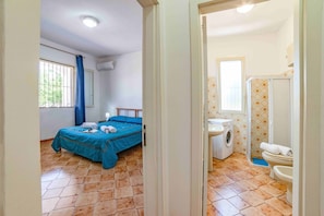 A bedroom with a bed, a window, and a bathroom with a washing machine and toilet. - Casa Spiaggiabella Near The Sea (Lecce)