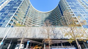 A modern building with a curved facade, multiple balconies, and a covered entrance area. - Modern City Stay with Scenic Parkland Views (Canberra)