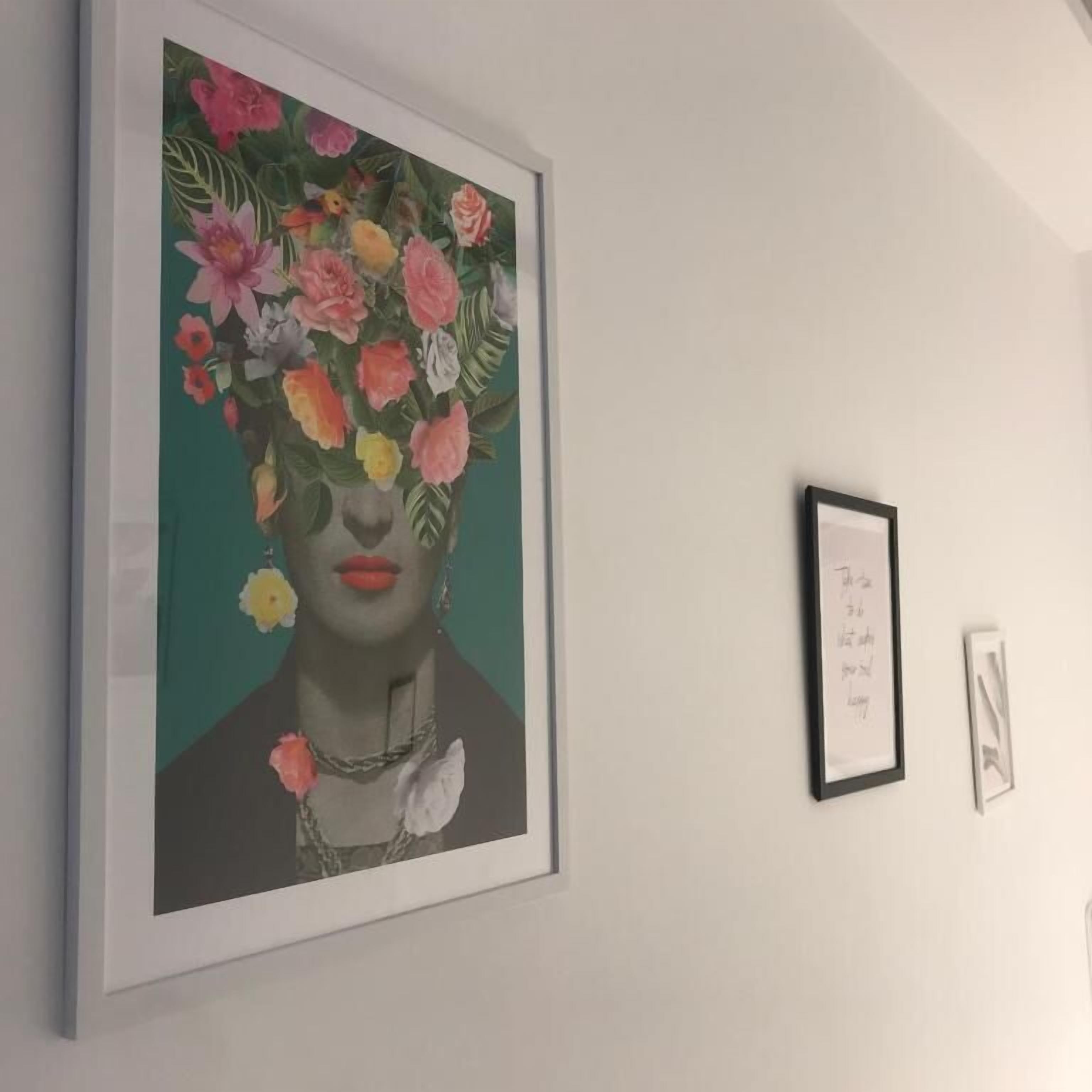 A framed artwork on a wall, a smaller framed piece to the right, and a third smaller piece below.