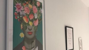 Une œuvre d’art encadrée est accrochée au mur, une autre œuvre, plus petite et également encadrée, se trouve à sa droite, et une troisième, encore plus petite, est placée en dessous.