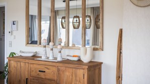 Un comò in legno con oggetti decorativi, un grande specchio e un lampadario.