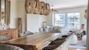 Un'area pranzo con un tavolo in legno, sedie in vimini e lampadari pendenti in vimini.
