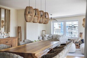 Ein Essbereich mit Holztisch, Korbstühlen und hängenden Lampen aus Korbgeflecht.