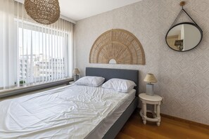 Ein Schlafzimmer mit einem Bett, einer Nachttischlampe, einem runden Spiegel und einem Wanddekor.